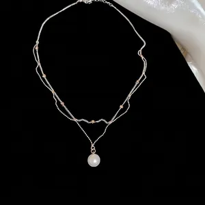 Élégant collier argenté à deux rangs avec un pendentif perle blanche sur fond noir profond
