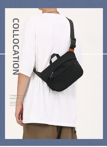 Detail of adjustable black nylon crossbody bag featuring an orange woven label accent