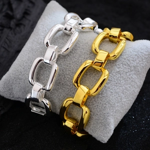 Fashionable hollow geometric gold and silver chain bracelets on a grey display pillow