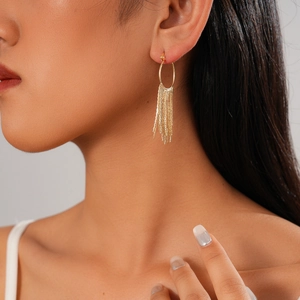 Elegant gold geometric circle drop earrings with fine tassel chains on a model