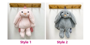 Detail view of pink and grey plush bunny backpacks with heart-shaped noses on wall hooks