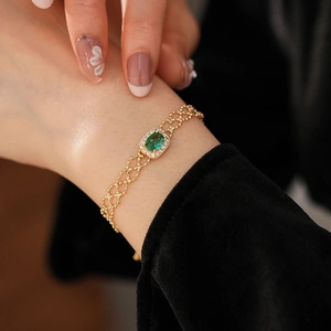 Detail of vintage gold bracelet featuring a green oval stone and zircon accents