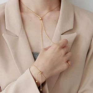 Dettaglio di un elegante set di gioielli d'oro abbinato a un raffinato blazer beige