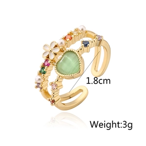 Detail of adjustable gold ring with green heart stone and colorful zircon accents