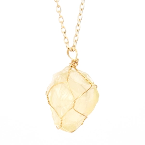Detail of a raw yellow crystal pendant with gold wire-wrapped design on a slim chain