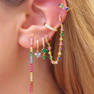 Macro shot of layered S925 silver hoop earrings with rainbow zircons and flower charms