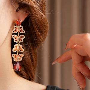 Gros plan de boucles d'oreilles papillon vintage dorées avec zircon rouge sur un mannequin