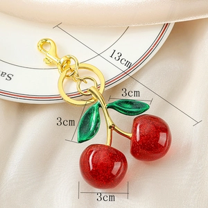 Detailed view of red glitter cherry keychain with dimensions on a white plate