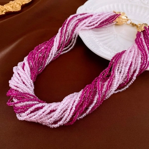 Detail view of multi-layer beaded necklace with pink and purple beads on silk