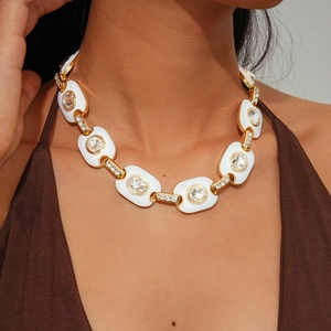 Close-up of vintage gold chunky chain necklace with white enamel and sparkling crystal inlay