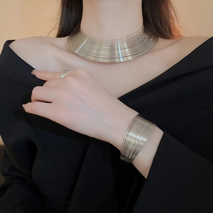 Close-up of a silver multi-layer metal necklace and bracelet set on a model