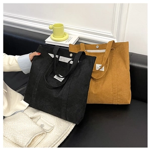 Black and brown corduroy tote bags displayed on a sofa in a modern interior setting