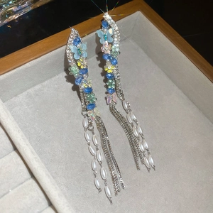Detailed macro of butterfly pearl tassel earrings with blue crystals and sparkling rhinestones
