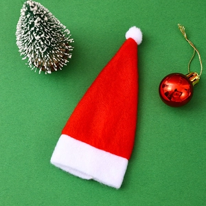 Mini red velvet Christmas hat utensil holder and wine bottle topper on green background