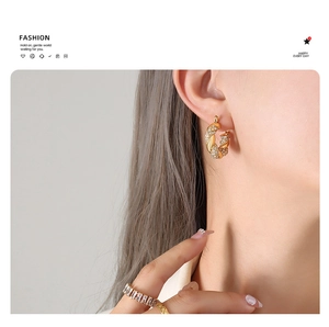 Detail of twisted gold U-shaped earrings with micro-set zircons on model ear