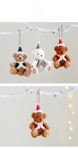 Three plush Christmas teddy bears in cozy outfits hanging as festive ornaments on white branches