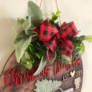 Detail of wooden Christmas door sign with red lettering and plaid bow decoration