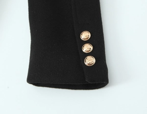 Detailed view of black wool coat cuff featuring three luxury embossed gold buttons