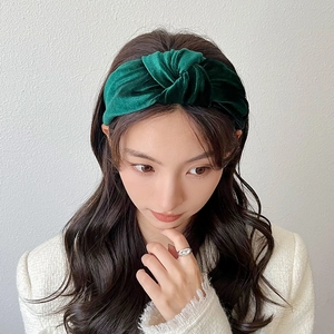 Close-up of dark green velvet knotted headband with high-gloss texture on woman
