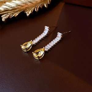 Macro detail of gold teardrop necklace with sparkling yellow zircon and crystal links