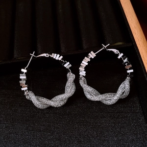 Vue détaillée des boucles d'oreilles créoles argentées tressées sur velours noir