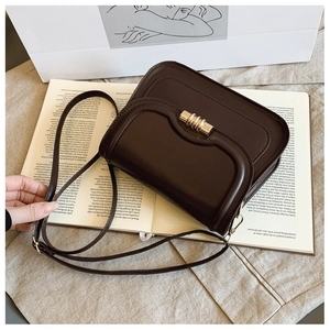 Vue détaillée du sac besace en cuir marron avec fermoir doré sur fond de livres rétro