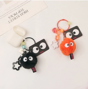 Cute fuzzy plush monster charm with big eyes attached to a white headphone case