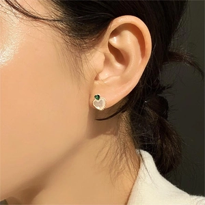 Detail of a 925 silver heart earring with green zircon and pearl on a woman's ear