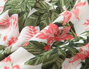 Détail d'un tissu léger et doux avec imprimés de feuilles vertes et fleurs tropicales