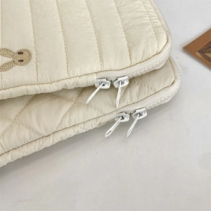 Detail of quilted tablet sleeve featuring white embroidery and dual zipper closure