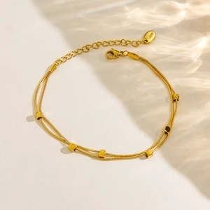 Détail du bracelet double couche en acier plaqué or 14K avec perles carrées et maille serpent