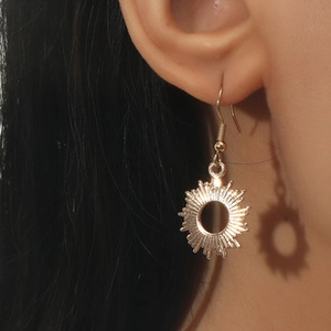 Macro detail of golden sunburst hoop earrings on model featuring a woven punk design