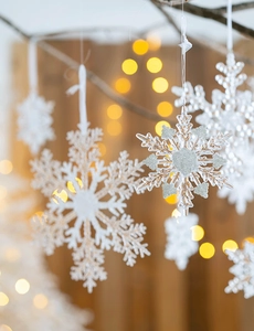 Macro detail of transparent acrylic snowflake ornaments with silver glitter hanging on tree