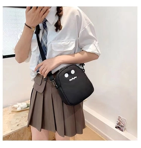 Gros plan sur le sac bandoulière noir avec motif minimaliste de monstre blanc mignon