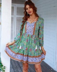 Dettaglio di un abito boho verde a fiori con scollo a V e bordo a balze con nappe