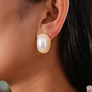 Close-up of a vintage oval pearl stud earring with intricate golden braided metal texture