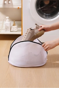 Placing a khaki sneaker into a thick white mesh wash bag for laundry machine protection