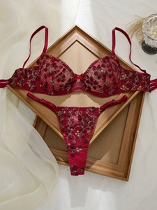 Gros plan détaillé sur un ensemble de lingerie en dentelle rouge avec broderie dorée
