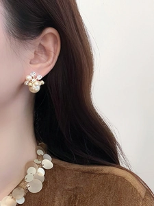Détail d'élégante boucle d'oreille fleur en perle et zircon plaquée or 18k sur modèle