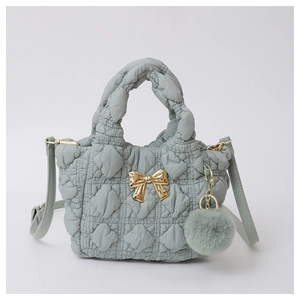 Detail of light green quilted cloud bag with gold bow and soft plush keychain