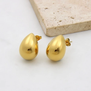 Detail of gold teardrop earrings with a smooth mirror finish and push-back design