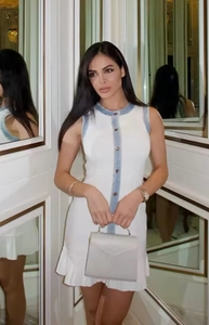 Détail de la robe tricotée blanche sans manches avec bordure bleu clair et boutons