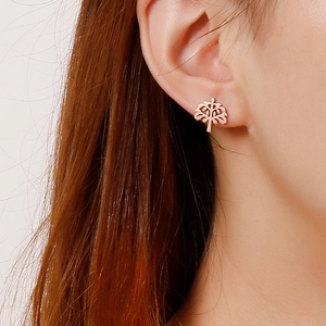 Rose gold tree of life stud earrings on female model's ear showing delicate metal texture