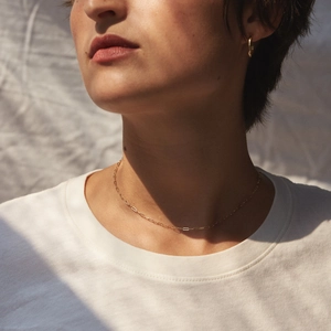 Gros plan détaillé d'un collier chaîne trombone doré porté par un mannequin sur t-shirt
