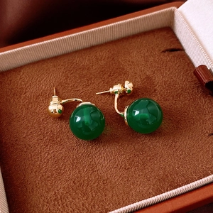 Detailed view of dark green sphere earrings on brown velvet jewelry box packaging