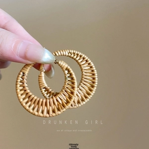 Macro shot of bohemian raffia woven hoop earrings with golden hooks and straw texture
