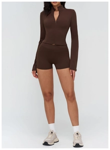 Detail of dark brown yoga set with high-waist cross shorts and stand-collar zip jacket