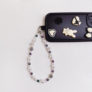 Detail of beaded phone strap with white pearls and metallic rose beads on black case