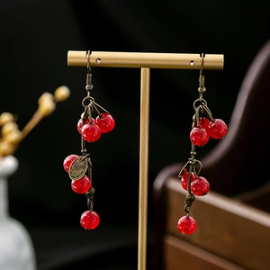 Detail of red cherry beaded long tassel earrings with bronze floral metal hollow accents