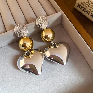 Chic gold and silver heart earrings with spiral texture on soft grey velvet display